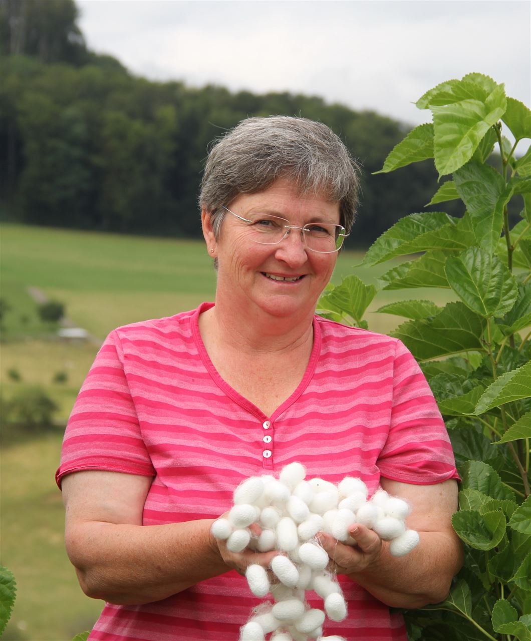 Katharina Bitterli mit Seidenkokons vor einem Maulbeerbaum