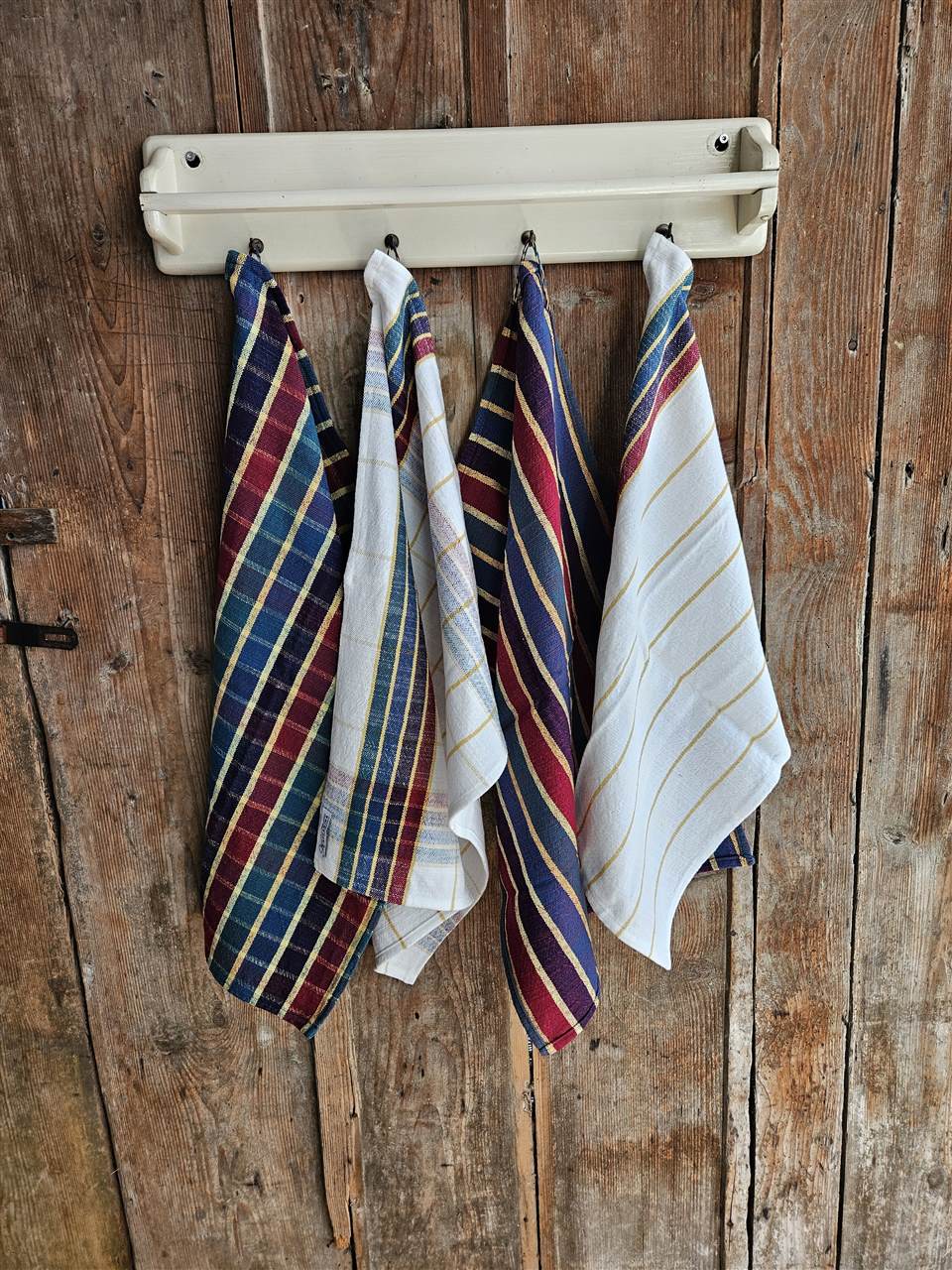 Küchen- und Handtücher mit bunten Karos und Streifen an einer Hakenleiste